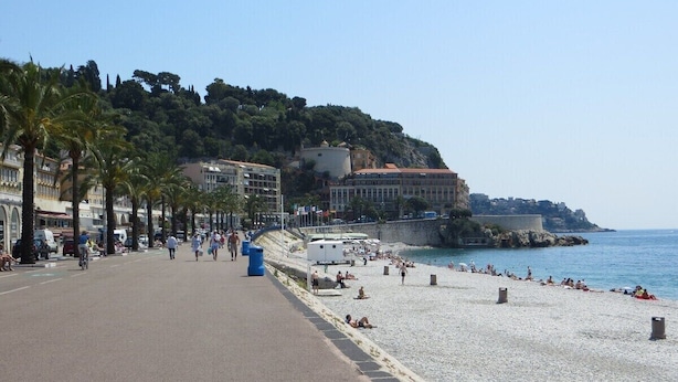 Une promenade en bord de mer avec une plage de galets, une voie piétonnière et des bâtiments en arrière-plan.