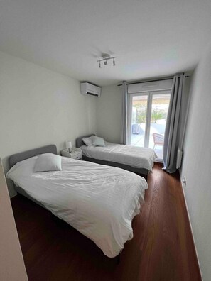 Ein Zimmer mit zwei Betten, einem Deckenventilator, einer Klimaanlage und Blick ins Freie.