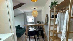 A compact living space with a wooden floor, a dining area with a table and chairs, a bunk bed with a wooden frame, and a hanging light fixture. - Beautiful refurbished cozy apartment (Nice)