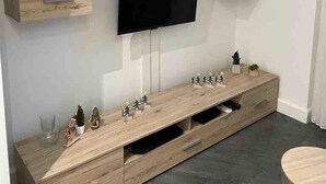 Ein modernes Wohnzimmer mit einem Holz-TV-Schrank, einem Flachbildfernseher und eingebauten Regalen.