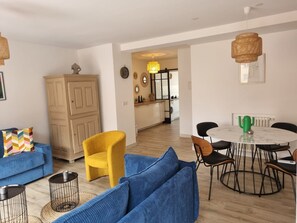 Ein Wohnzimmer mit einer Couch, einem Sessel und einem Esstisch mit Stühlen.