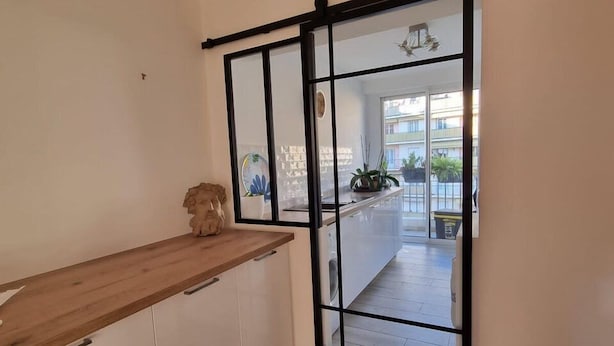 Cozinha com bancada de madeira, armários brancos e porta de vidro deslizante para uma varanda.