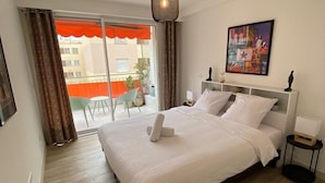 Quarto de hotel com uma cama, um quadro, uma luminária no teto e vista para o exterior.
