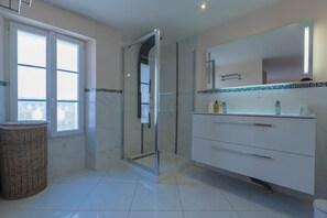 A modern bathroom with a glass-enclosed shower, a white vanity with a mirror, and a wicker basket. - Agréable et Cosy - Suquet - proche des plages (Cannes)