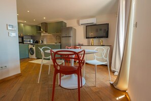 A compact kitchen with modern appliances, a dining area with a round table and chairs, and a flat-screen TV mounted above the counter. - Agréable et Cosy - Suquet - proche des plages (Cannes)
