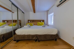 Ein Hotelzimmer mit einem großen Bett, einem Spiegel, einem Fenster und einer Klimaanlage.