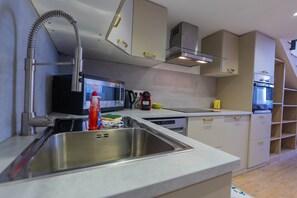 Eine moderne Küche mit Edelstahlgeräten, einer eingebauten Mikrowelle und einem Spülbecken.