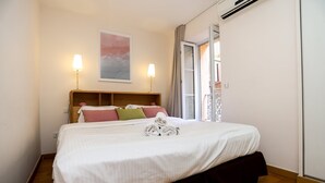 Ein Hotelzimmer mit einem großen Bett, zwei Nachttischlampen, einem Gemälde an der Wand und einem Fenster mit Vorhängen.