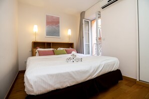 Een hotelkamer met een groot bed, twee bedlampen, een schilderij aan de muur en een raam met gordijnen.