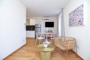 Een moderne keuken met witte kasten, een ingebouwde oven en een flatscreen televisie.