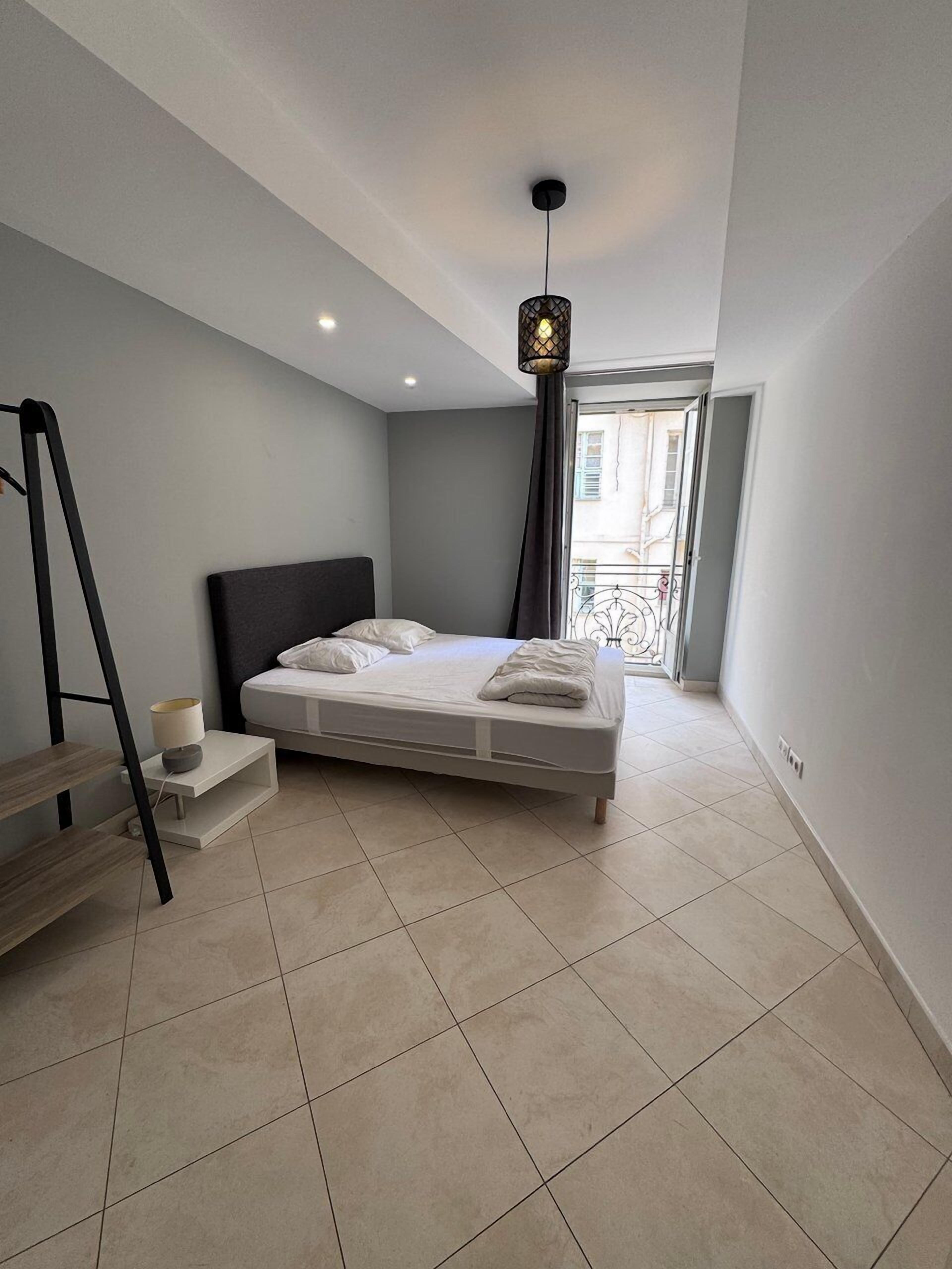 Une chambre moderne avec un lit, une table de chevet, une lampe et une vue sur l’extérieur.