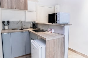 Eine kleine Küchenzeile mit Spüle, Mikrowelle, Kaffeemaschine und kleinem Kühlschrank.