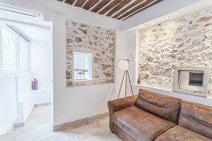 Ein modernes Wohnzimmer mit Steinwand, brauner Ledersofa, Stehlampe und einem gerahmten Bild.