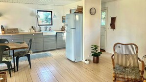 Una cocina moderna con armarios grises, un refrigerador blanco y una zona de comedor con mesa y sillas de madera.