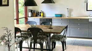 Una cocina moderna con una mesa y sillas de madera, una estufa y un ventanal grande.