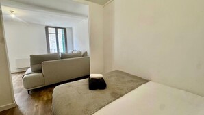 A minimalist room with a bed, a sofa, and a window.