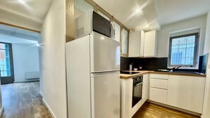 A kitchen with a refrigerator, oven, microwave, and wooden countertop.