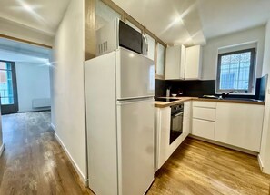 Eine Küche mit Kühlschrank, Backofen, Mikrowelle und einer Holzarbeitsplatte.