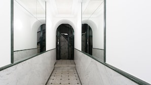 Een gang met marmeren vloer, een metalen poort en spiegelwanden.