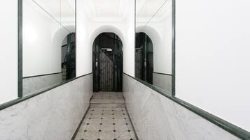 A hallway with marble flooring, a metal gate, and mirrored walls.