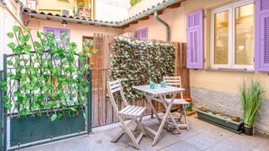 Een terras met een tafel en stoelen, een bamboescherm en een plant in pot.