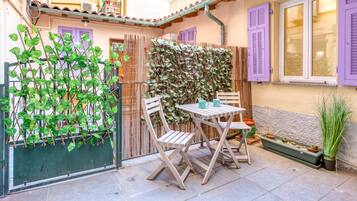 An outdoor seating area with a table and chairs, a bamboo fence, and a potted plant.