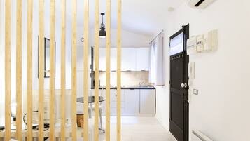 A modern kitchen with white cabinets, a black countertop, and a hanging light fixture.
