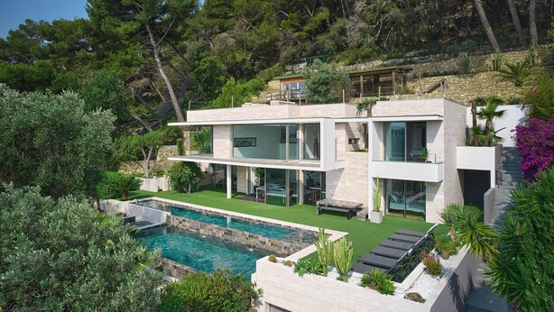 Una moderna casa a due piani con piscina, immersa nel verde e alberi rigogliosi.