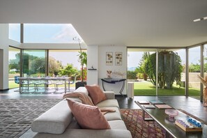 Ein modernes Wohnzimmer mit Sofa, Couchtisch und Essbereich mit Glastisch und Stühlen.