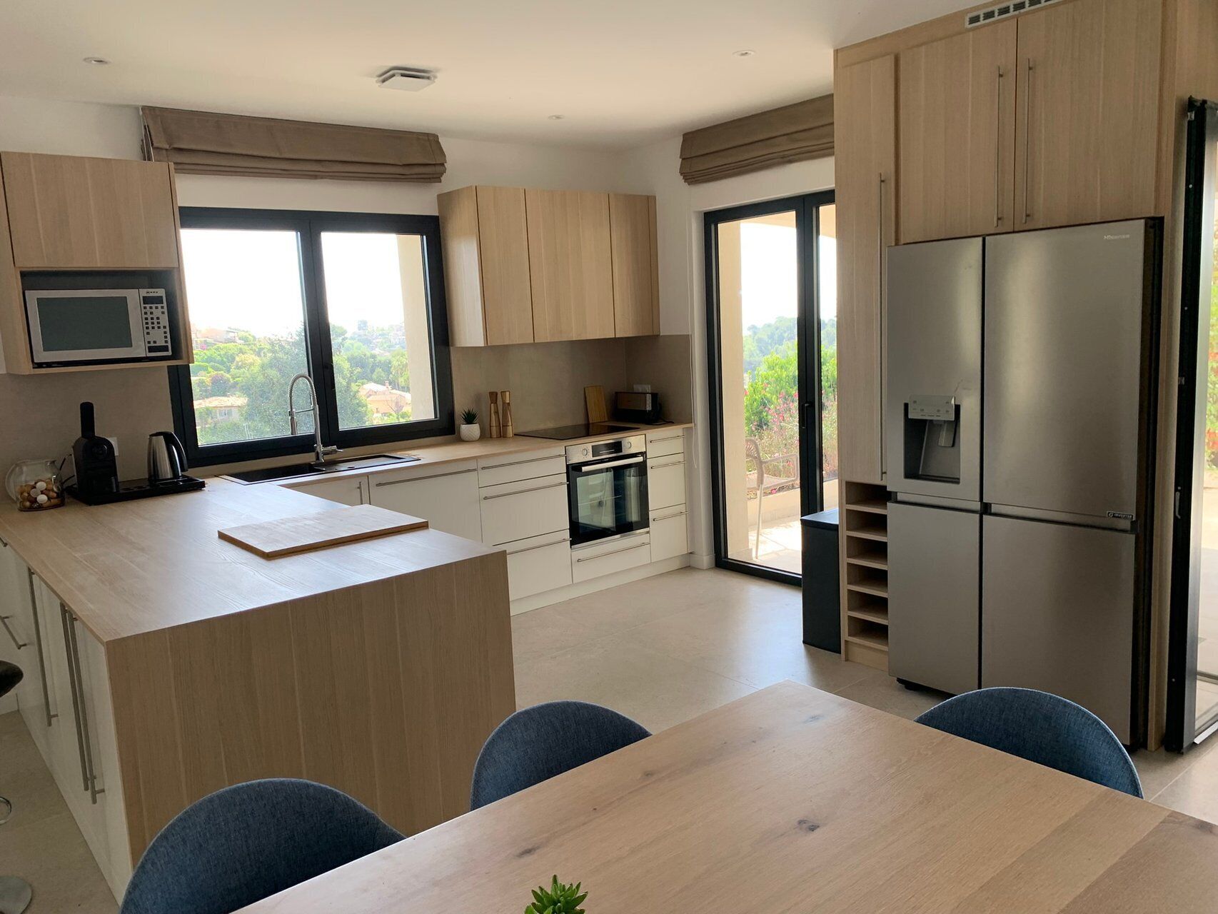A modern kitchen with a central island, built-in appliances, and a sliding glass door to a balcony.