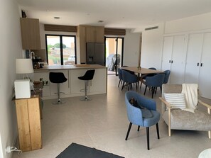 A modern kitchen with a dining area, bar stools, and a view of the outdoors. - Superbe villa et piscine - 3 appartements (Cagnes-sur-Mer)