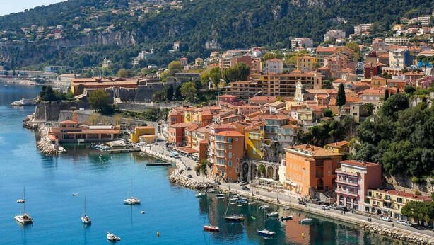 A coastal town with buildings along the waterfront, a harbor with boats, and a hilly backdrop. - Charmant studio rénové – Place de la République (Villefranche-sur-Mer)