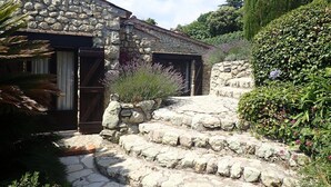 A stone building with a rustic entrance, steps leading up to a door, and a garden with various plants. - Authentic & Atypical house - Vence (Vence)