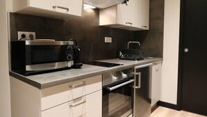 A modern kitchen with white cabinetry, a built-in oven, a microwave, and a stove. - Superbe Appartement moderne au coeur du Vieux Nice (Nice)
