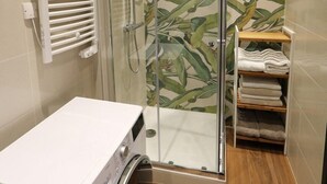 A compact bathroom with a glass shower enclosure, a built-in washing machine, and a towel rack. - Superbe Appartement moderne au coeur du Vieux Nice (Nice)