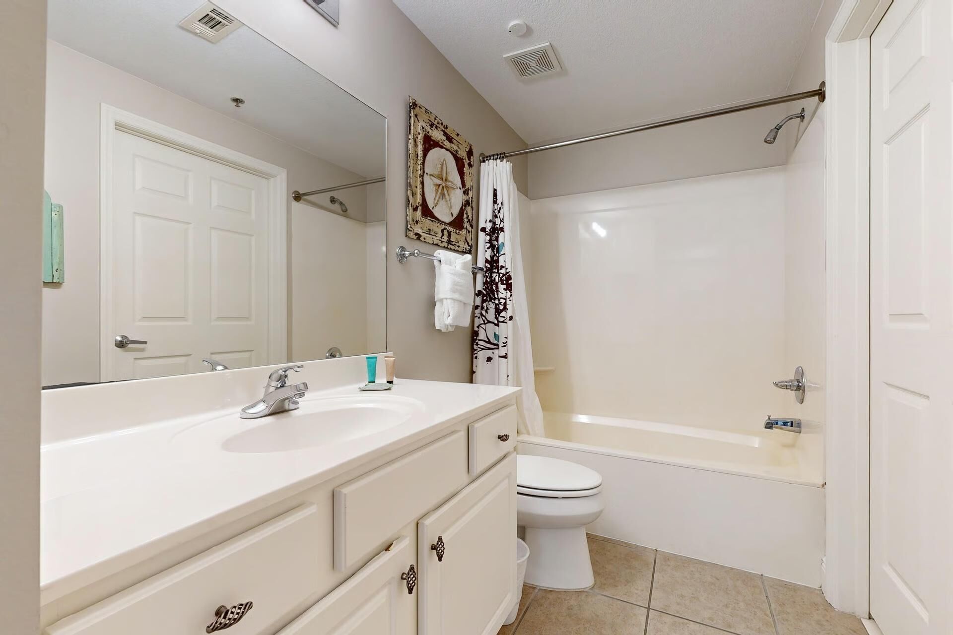 A bathroom with a white sink, vanity, toilet, and bathtub.