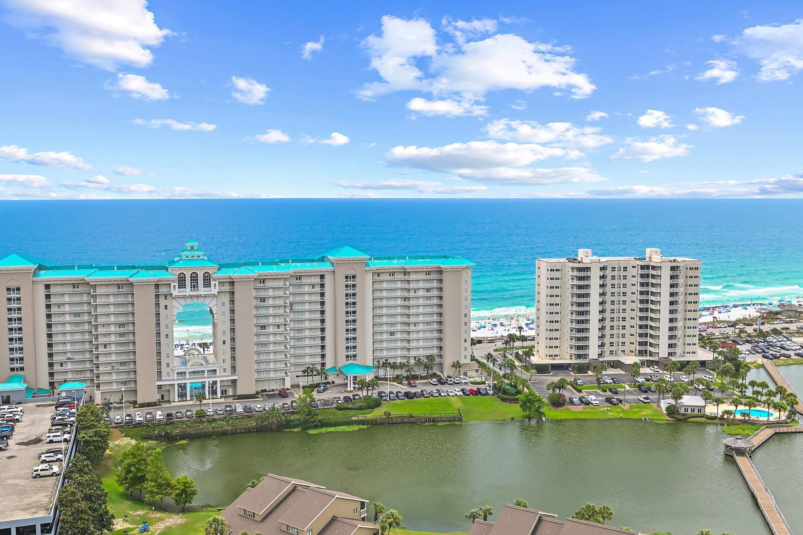 A high-rise hotel with multiple balconies overlooking a body of water and a beach.