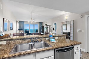 Eine moderne Küche mit Granit-Arbeitsplatten, Edelstahlgeräten und Blick ins Freie.