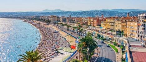A coastal cityscape with a beach, buildings, and a clear sky.