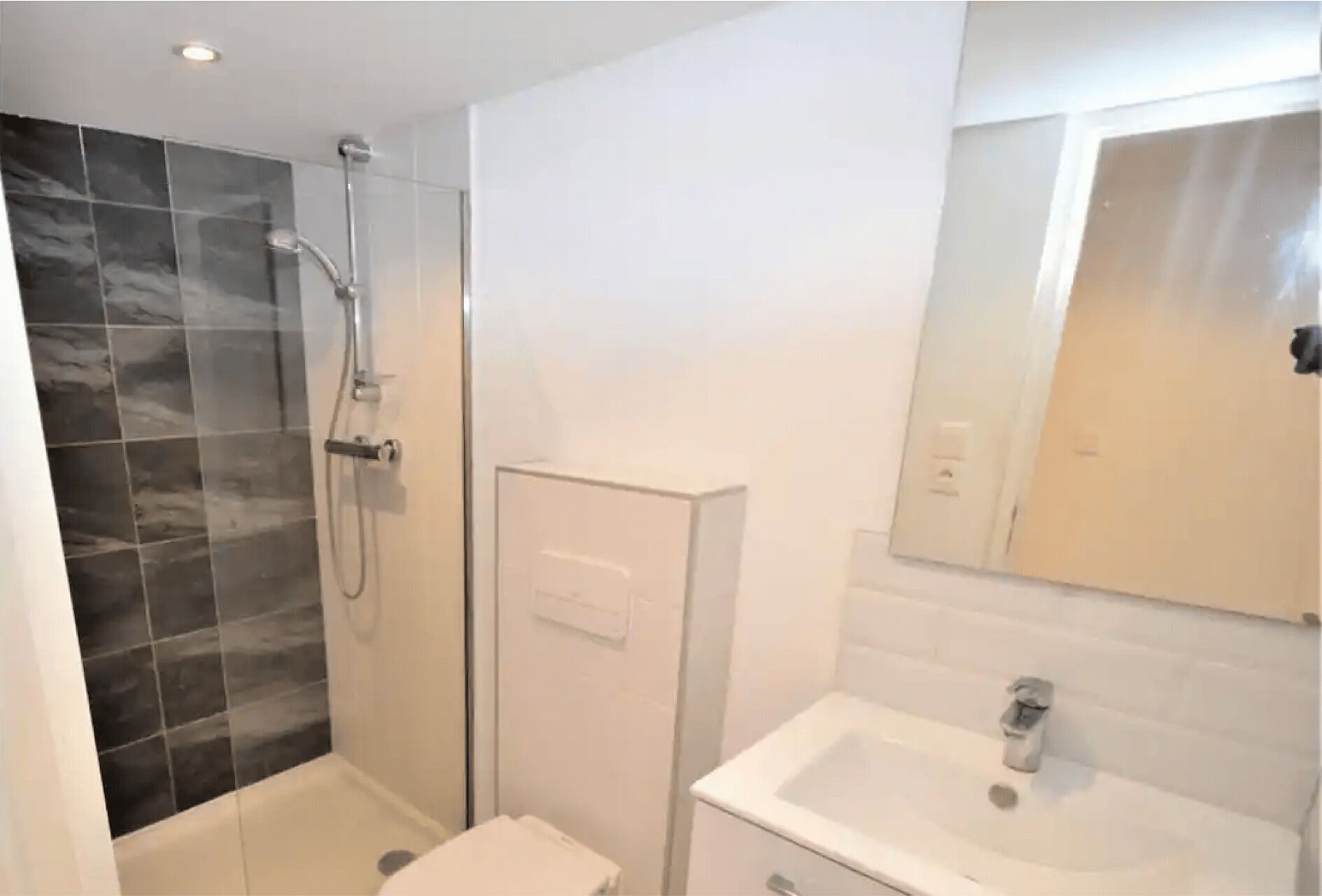 A bathroom with a shower, a sink, and a mirror.