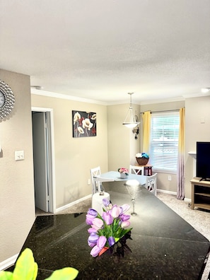 A modern kitchen with a black countertop, a dining table with chairs, a chandelier, and a painting on the wall. - 2BR  2Bth  NRG  MDA Med DT  UH Zo 2KgBd. Pool Museums Galleria 2 KgBds 4KTV WiFi (Houston)