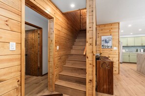 Eine Holztreppe in einem rustikalen Interieur, im Hintergrund ist eine Küchenzeile erkennbar.