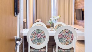 A dining area with a white table, floral chairs, a vase with flowers, and a pendant light. - Apartamento verão na praia (Vila Velha)