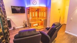 Quarto com cadeira de massagem, televisão na parede e sauna.