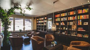 Uma biblioteca com poltronas de couro, estantes de livros e uma grande janela.