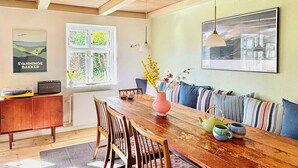Un área de comedor con una mesa de madera, sillas, un sofá y un radiador.