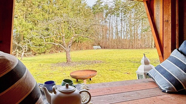 Una terraza de madera con una mesa, una tetera y un farol.
