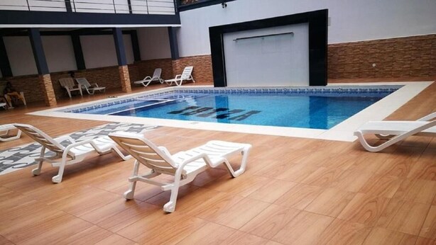An indoor swimming pool with lounge chairs and a tiled floor.
