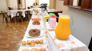 A breakfast buffet with pastries, a juice pitcher, and a variety of fruits.