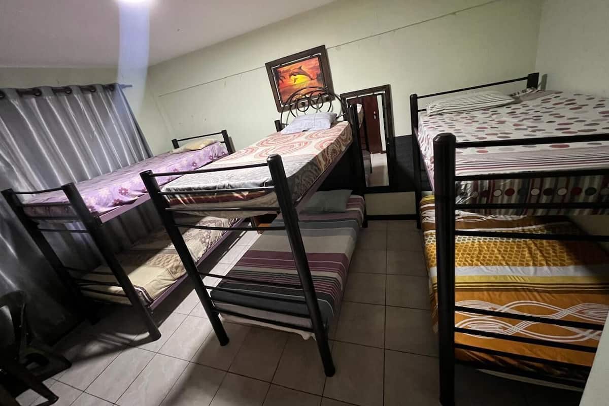 Habitación tipo dormitorio con literas, un cuadro en la pared y una cortina.